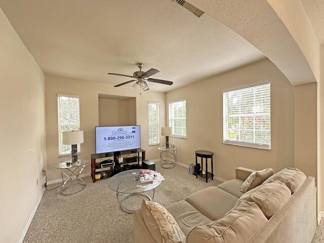 carpeted living room featuring ceiling fan and a textured ceiling