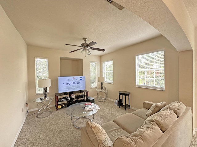 carpeted living room featuring ceiling fan, visible vents, baseboards, and a textured ceiling