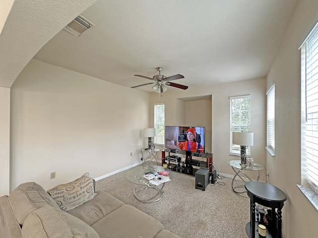 living room featuring visible vents, ceiling fan, baseboards, and carpet