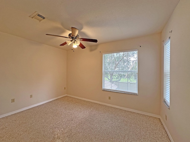 spare room featuring visible vents, baseboards, a textured ceiling, and carpet flooring