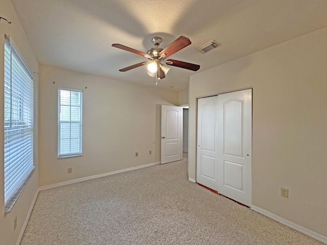 unfurnished bedroom with visible vents, a ceiling fan, a closet, baseboards, and light colored carpet