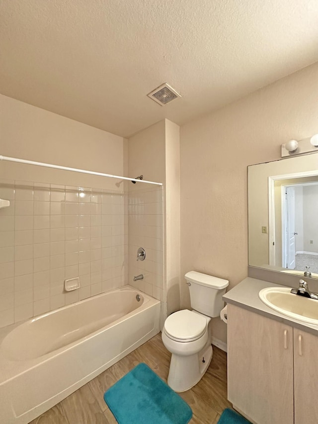 full bath with a textured ceiling, wood finished floors, visible vents, shower / bath combination, and toilet