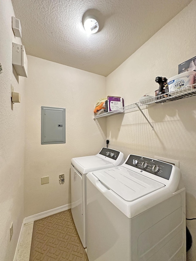 laundry room featuring electric panel, a textured ceiling, laundry area, and washing machine and clothes dryer