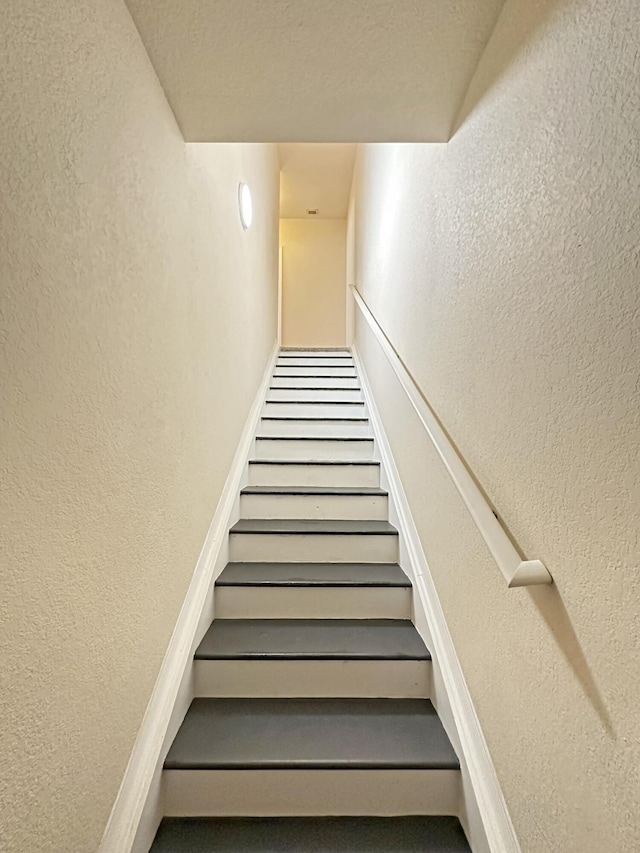 stairs featuring a textured wall and a textured ceiling