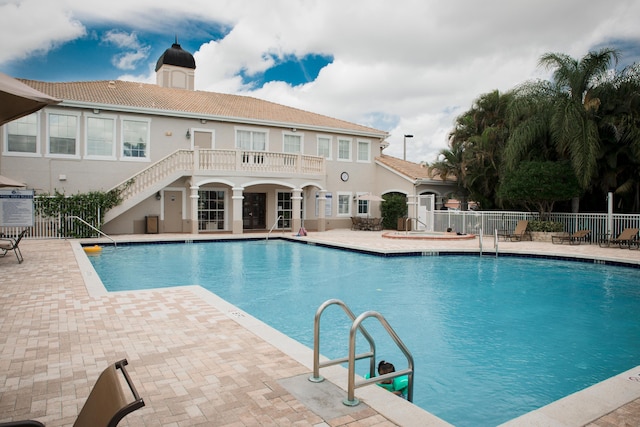 pool with a patio, stairs, and fence