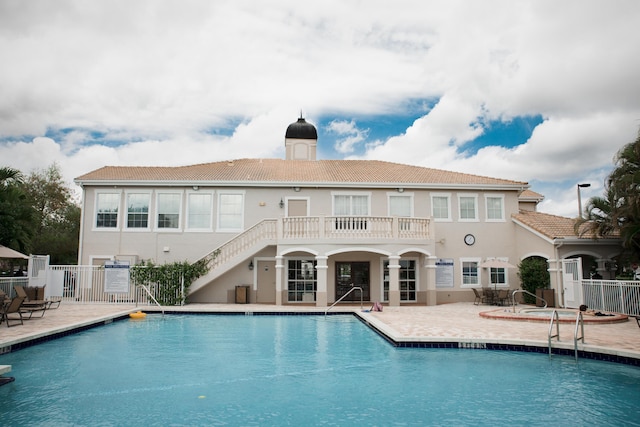 rear view of property featuring a patio, fence, a chimney, stucco siding, and a community pool