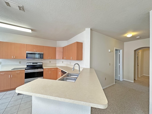 kitchen with visible vents, a peninsula, a sink, light countertops, and appliances with stainless steel finishes