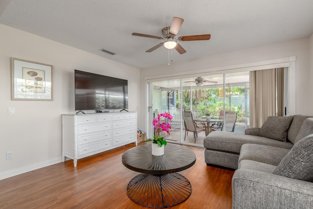 living room featuring a textured ceiling, ceiling fan, and dark hardwood / wood-style floors