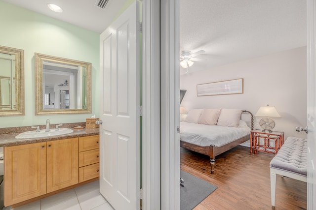 bedroom with a textured ceiling, ceiling fan, sink, and light hardwood / wood-style floors