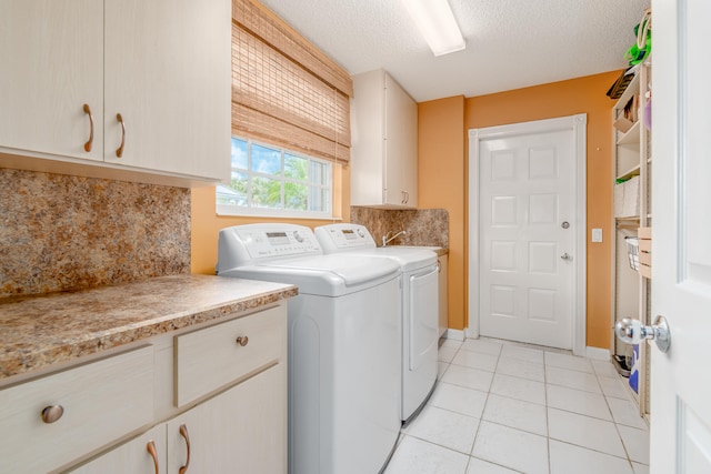 laundry room featuring a textured ceiling, cabinets, washing machine and dryer, and light tile patterned floors