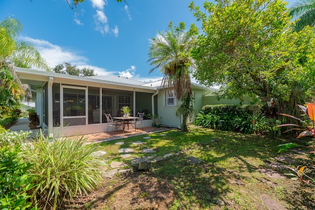 back of house featuring a lawn, a patio area, and a sunroom