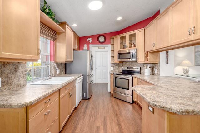 kitchen featuring light hardwood / wood-style flooring, stainless steel appliances, lofted ceiling, light brown cabinets, and decorative backsplash