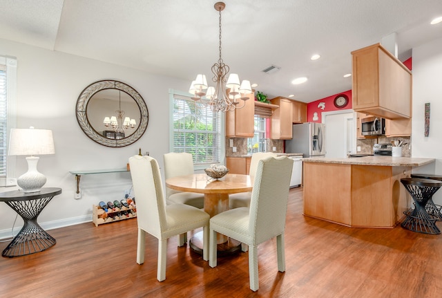 dining area with lofted ceiling, light hardwood / wood-style flooring, a notable chandelier, and a textured ceiling