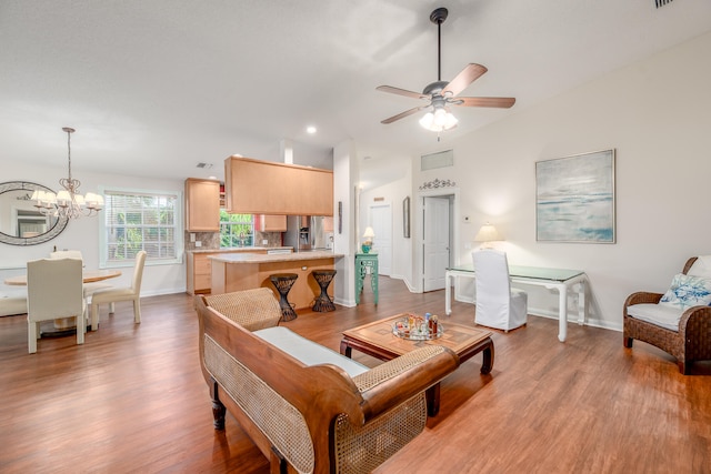 living room with lofted ceiling, ceiling fan with notable chandelier, and light wood-type flooring