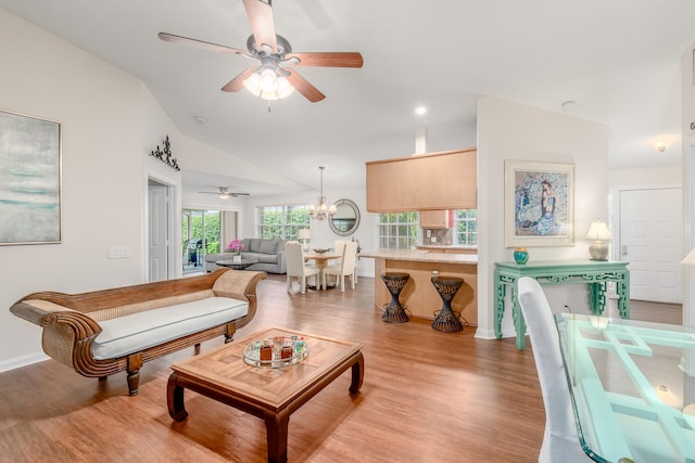 living room with ceiling fan with notable chandelier, vaulted ceiling, and hardwood / wood-style floors