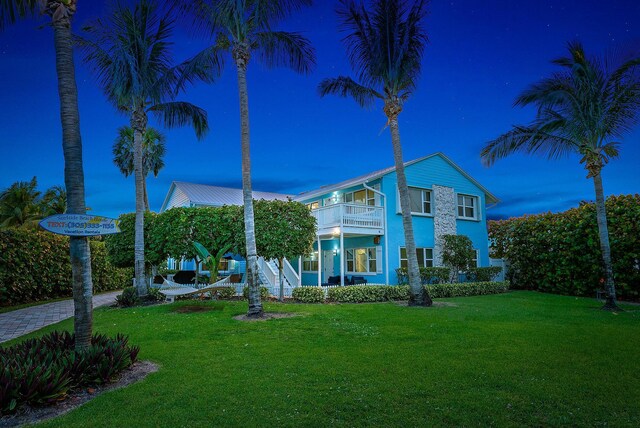 yard at dusk featuring covered porch and a balcony