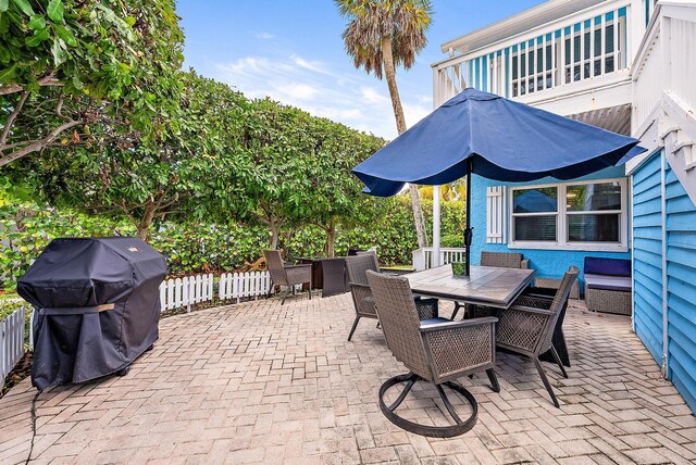 view of patio featuring a grill, fence, and outdoor dining space