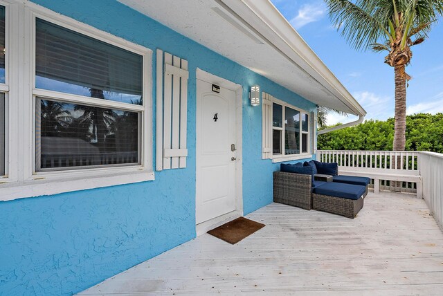 property entrance with a wooden deck and stucco siding