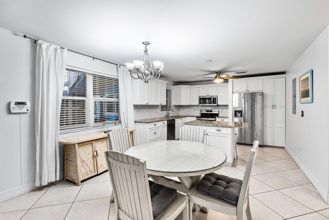 dining room with light tile patterned floors, baseboards, and ceiling fan with notable chandelier