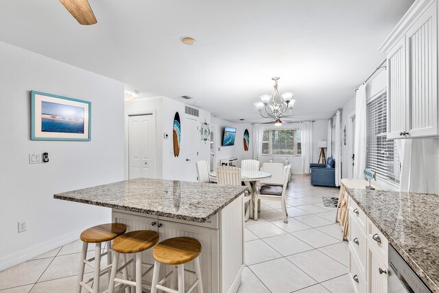 kitchen with light stone counters, light tile patterned flooring, a kitchen island, and white cabinetry