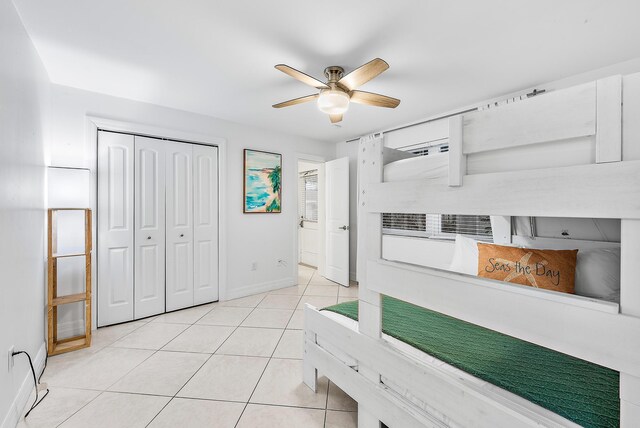 bedroom with light tile patterned floors, a ceiling fan, baseboards, and a closet