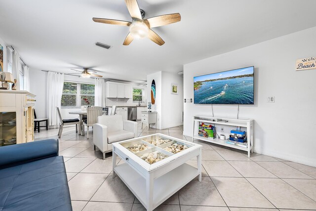 living area with visible vents, ceiling fan, baseboards, and light tile patterned floors