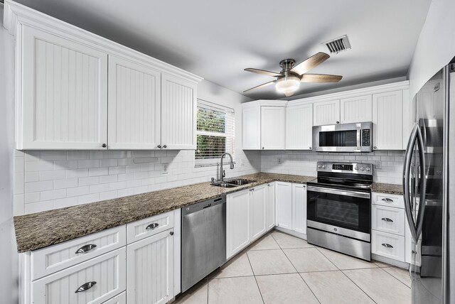 kitchen featuring a sink, visible vents, white cabinets, appliances with stainless steel finishes, and dark stone counters