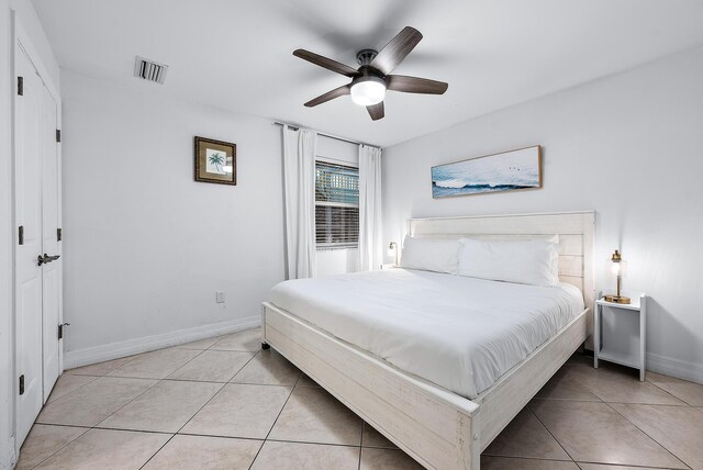 bedroom with light tile patterned floors, a ceiling fan, visible vents, and baseboards