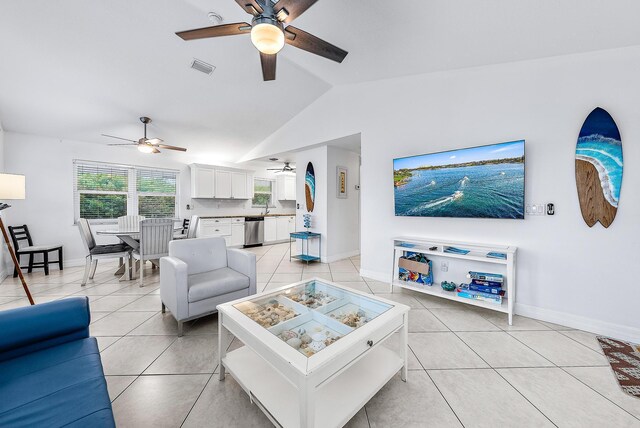 living room featuring a ceiling fan, lofted ceiling, baseboards, and light tile patterned floors