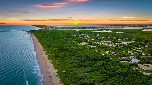 aerial view at dusk with a beach view and a water view