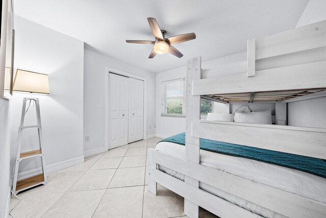 bedroom with light tile patterned floors, a closet, a ceiling fan, and baseboards