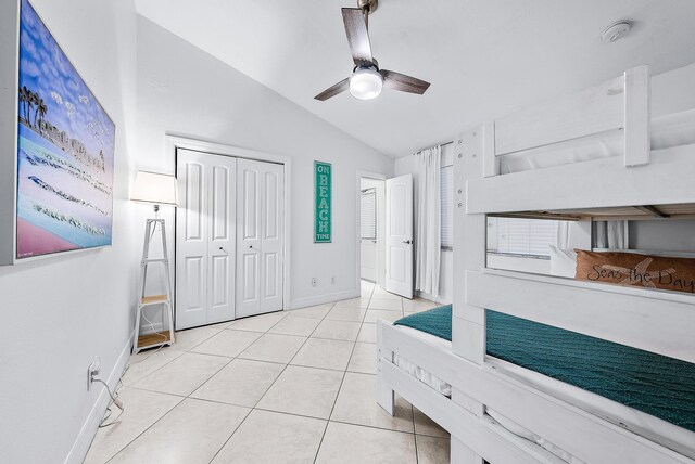 bedroom with light tile patterned floors, baseboards, a ceiling fan, lofted ceiling, and a closet