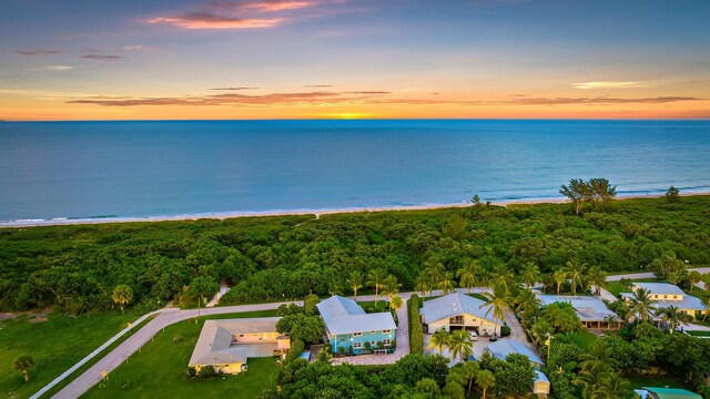 aerial view at dusk with a water view and a view of the beach