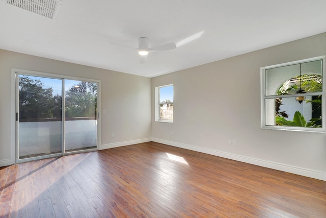 spare room featuring ceiling fan, a wealth of natural light, and wood-type flooring