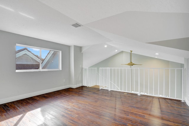 additional living space featuring dark wood-type flooring, a textured ceiling, and vaulted ceiling