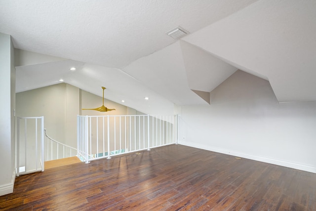 bonus room with dark hardwood / wood-style flooring, lofted ceiling, and a textured ceiling