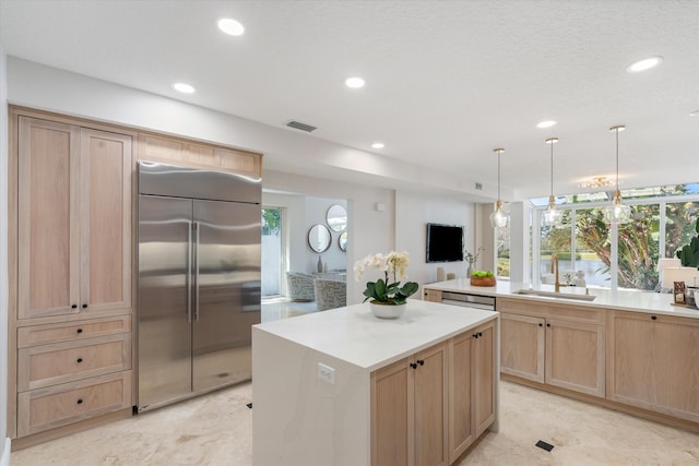 kitchen featuring a kitchen island, light brown cabinets, hanging light fixtures, and stainless steel appliances