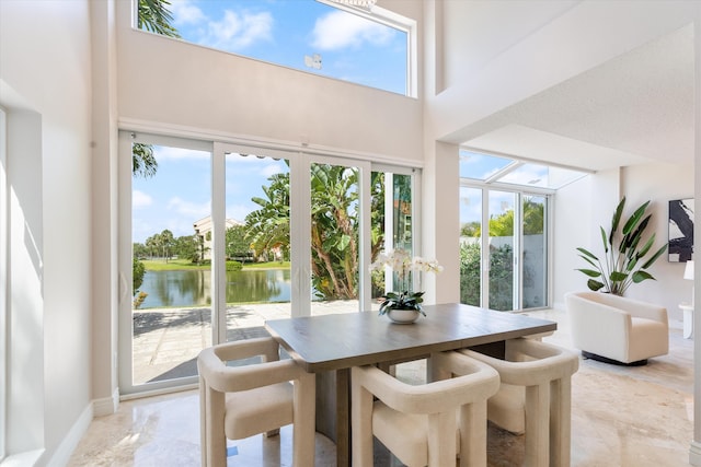 dining room featuring a wealth of natural light, a high ceiling, and a water view