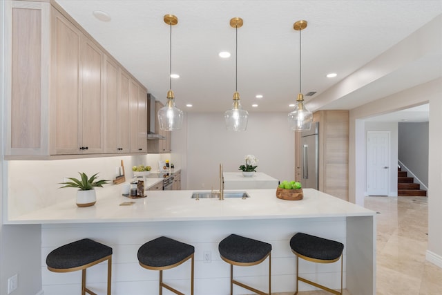 kitchen featuring light brown cabinets, kitchen peninsula, appliances with stainless steel finishes, and sink