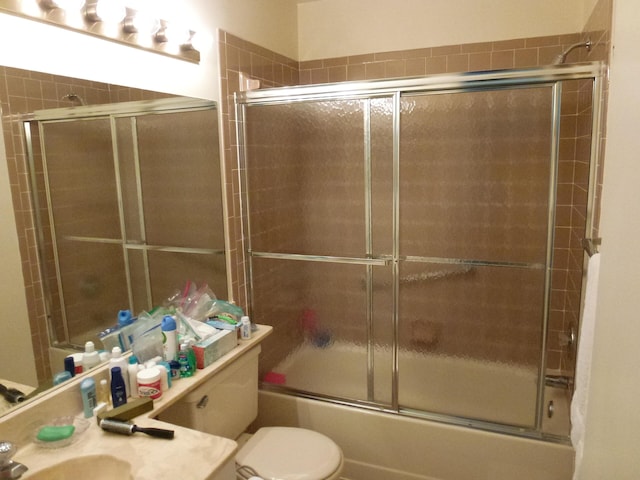 bathroom featuring toilet, bath / shower combo with glass door, and vanity