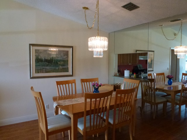 dining space with dark hardwood / wood-style flooring, a textured ceiling, and an inviting chandelier