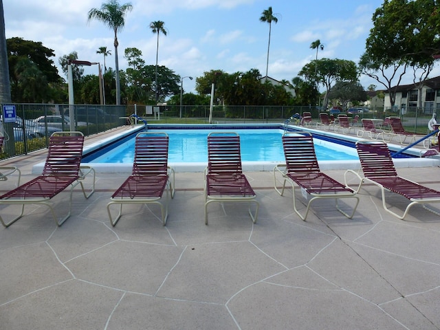 community pool with a patio area and fence