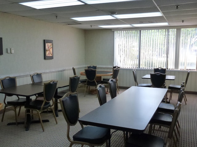 dining space with carpet floors and a drop ceiling