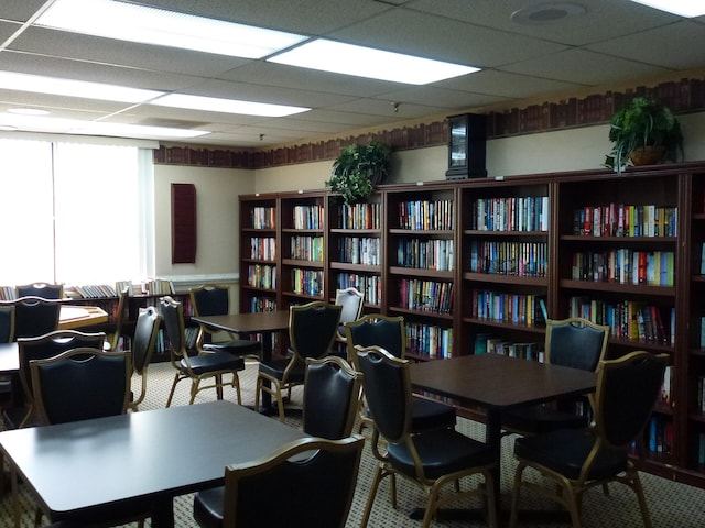 interior space with a drop ceiling and wall of books