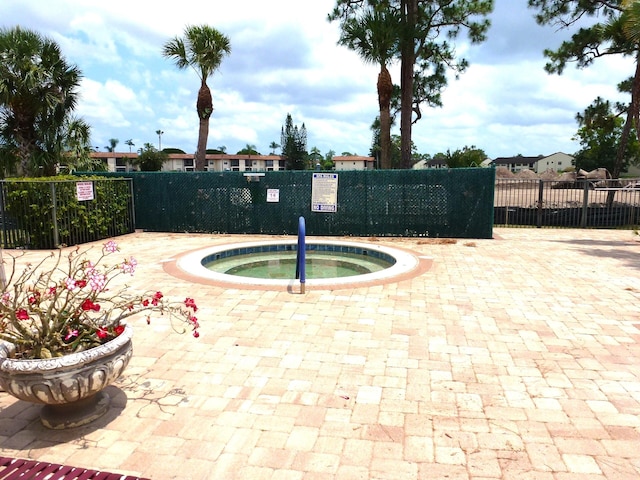 view of pool with a community hot tub and fence