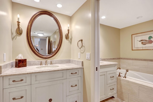 bathroom with tiled tub and vanity