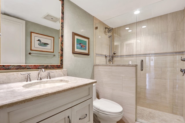 bathroom featuring vanity, a shower with shower door, and toilet