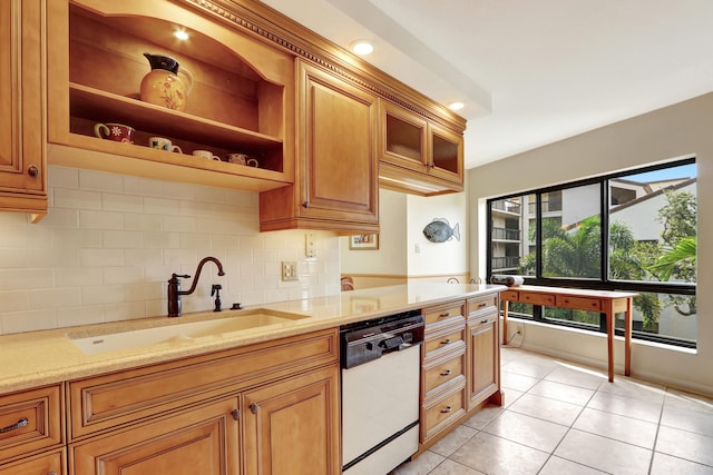 kitchen featuring light stone counters, white dishwasher, sink, light tile patterned floors, and backsplash