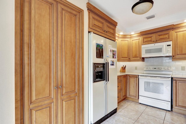 kitchen featuring backsplash, light tile patterned floors, and white appliances