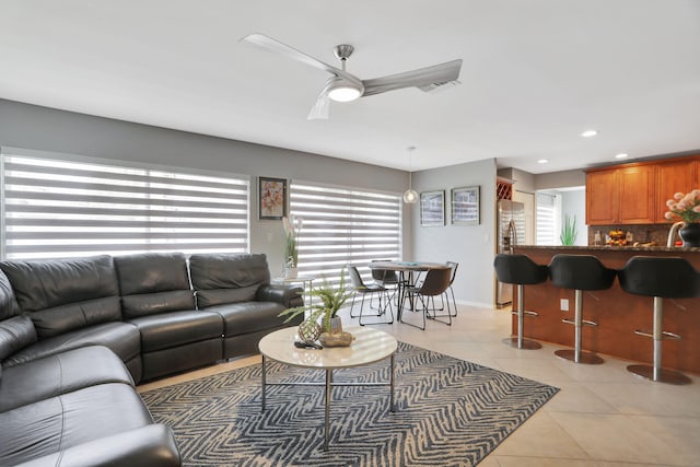 living room with ceiling fan, indoor bar, light tile patterned floors, and a wealth of natural light